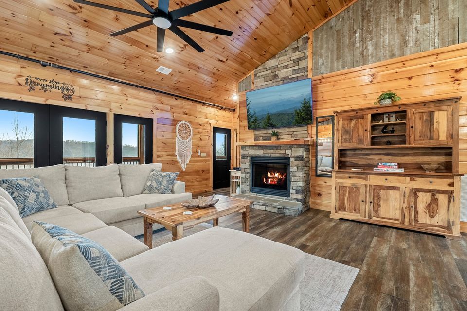 Great room with stone fireplace, sectional sofa and vaulted wood ceiling