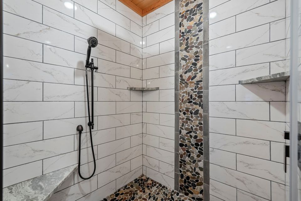 Walk-in tiled shower with river-stone accent